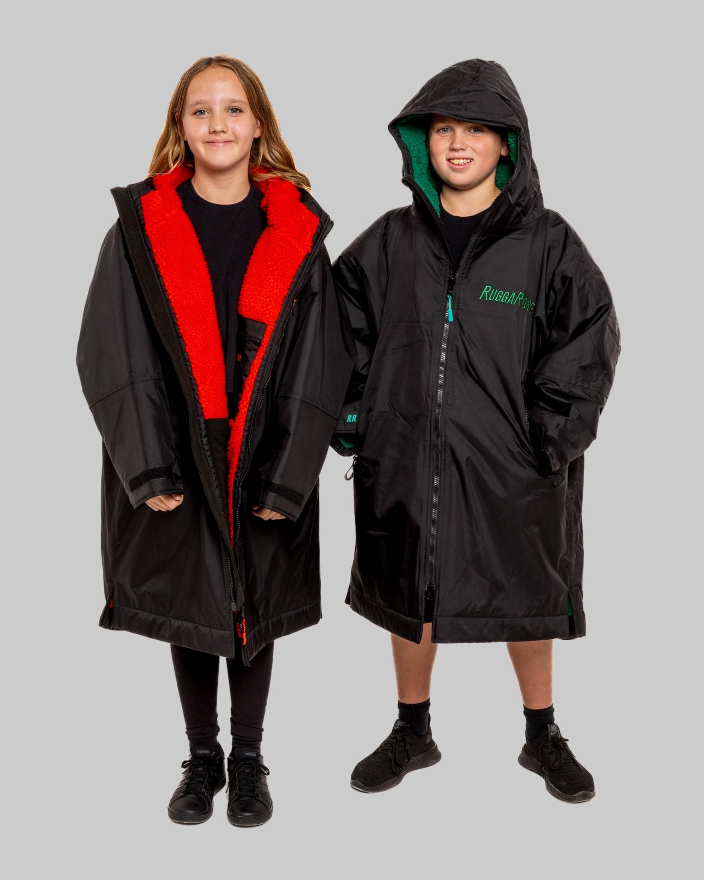 Two children wearing black with green and red interior accents on a gray background