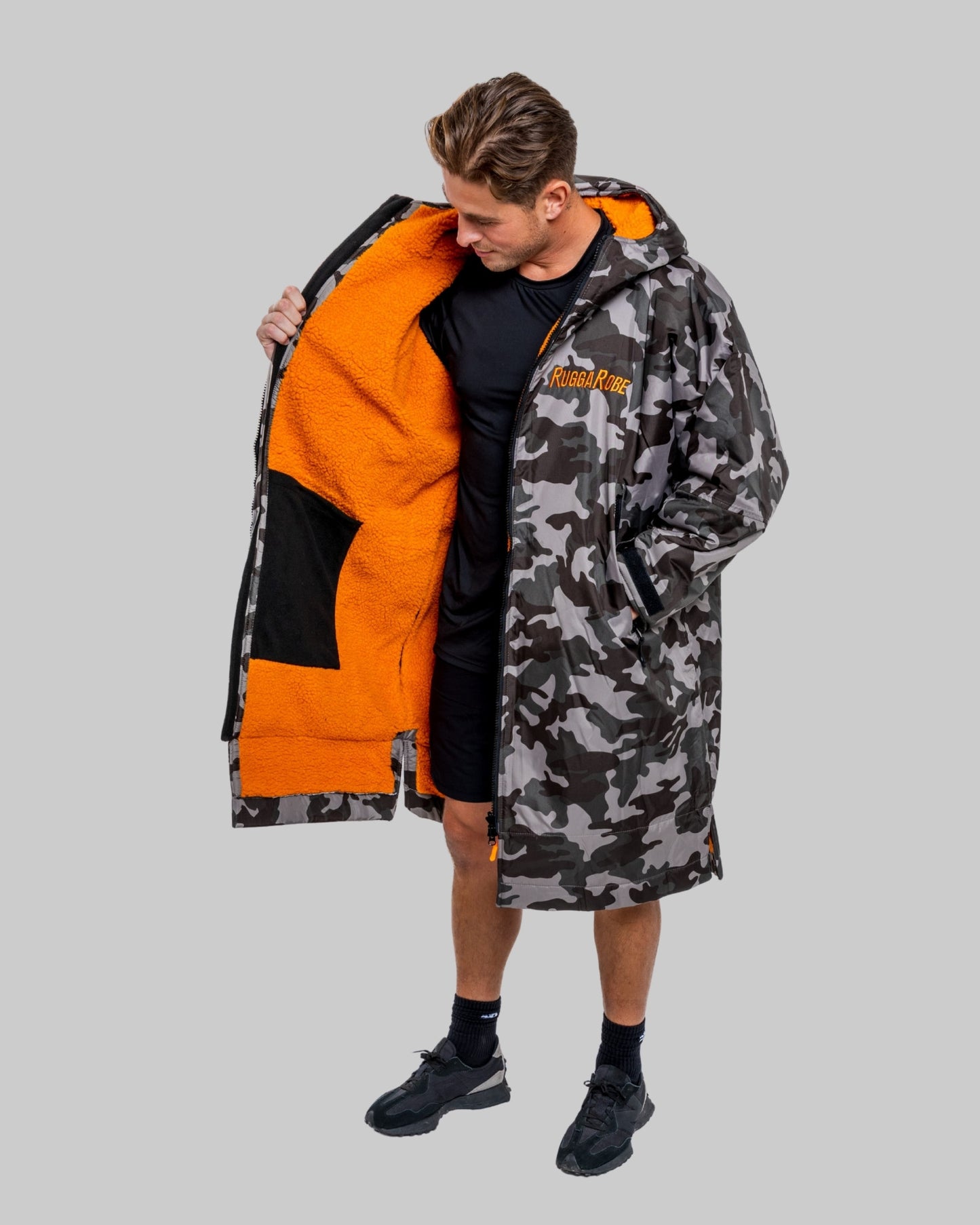 Model wearing RuggaRobe grey camo change robe with orange fleece interior on grey background