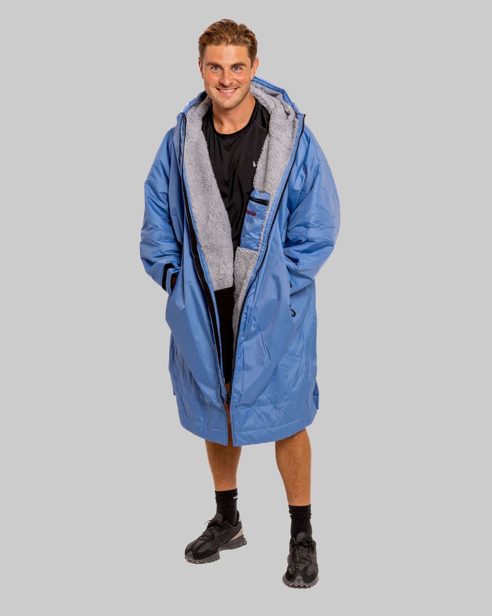 Man wearing a pale blue with grey Ffeece  ruggarobe on a gray background
