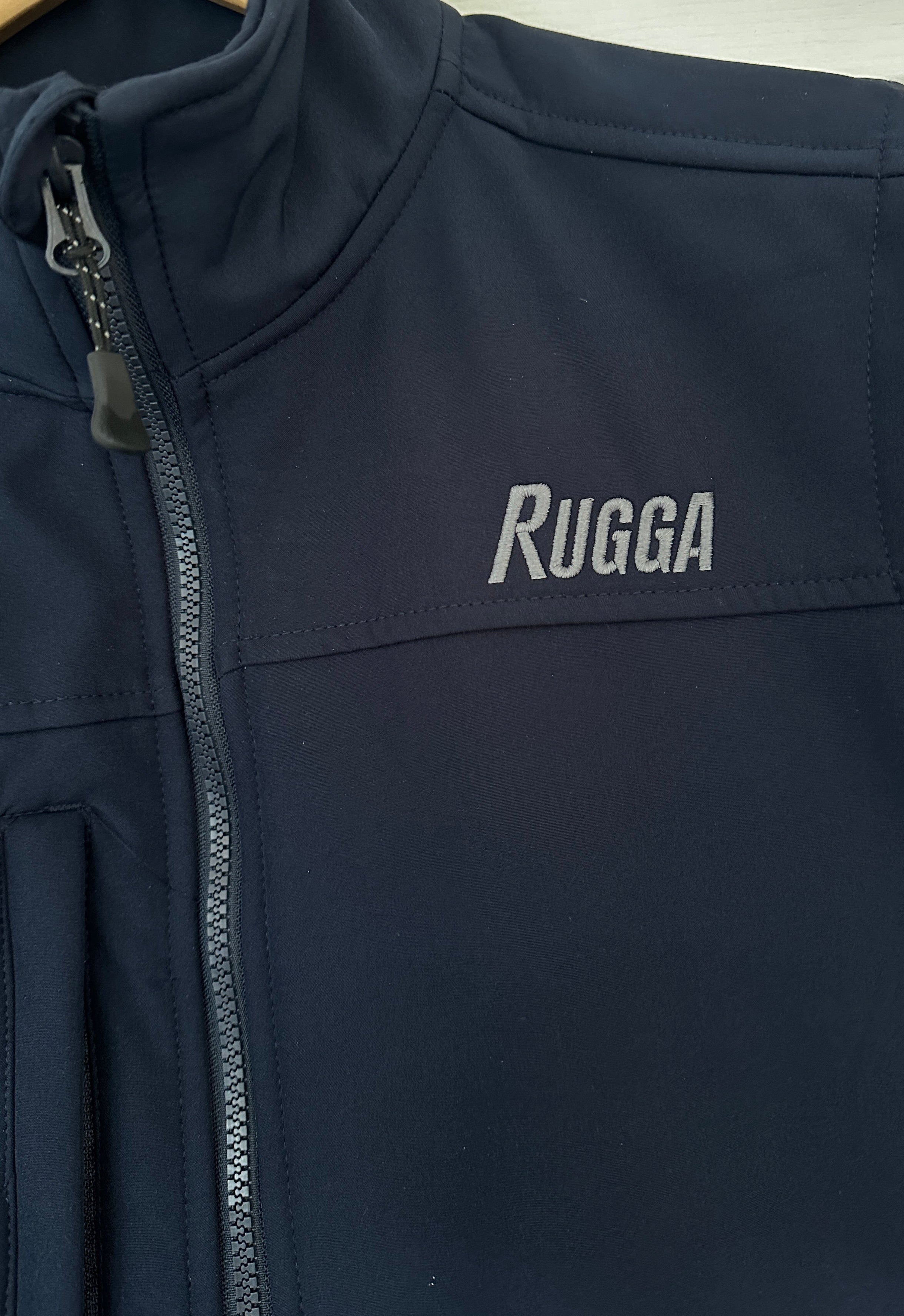 Navy blue jacket with 'Rugga' branding on a light background