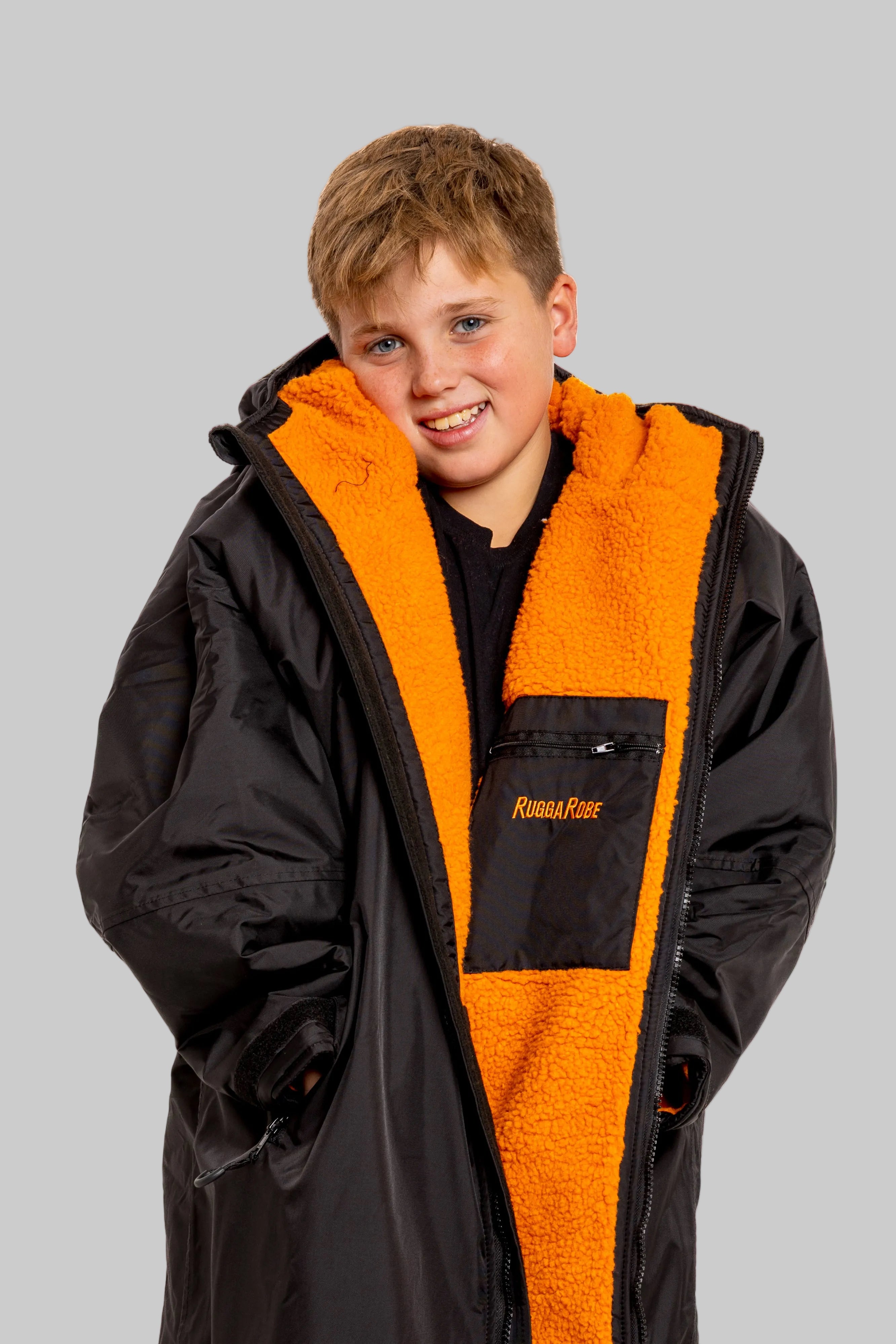 Model wearing RuggaRobe black change robe with orange fleece interior on grey background
