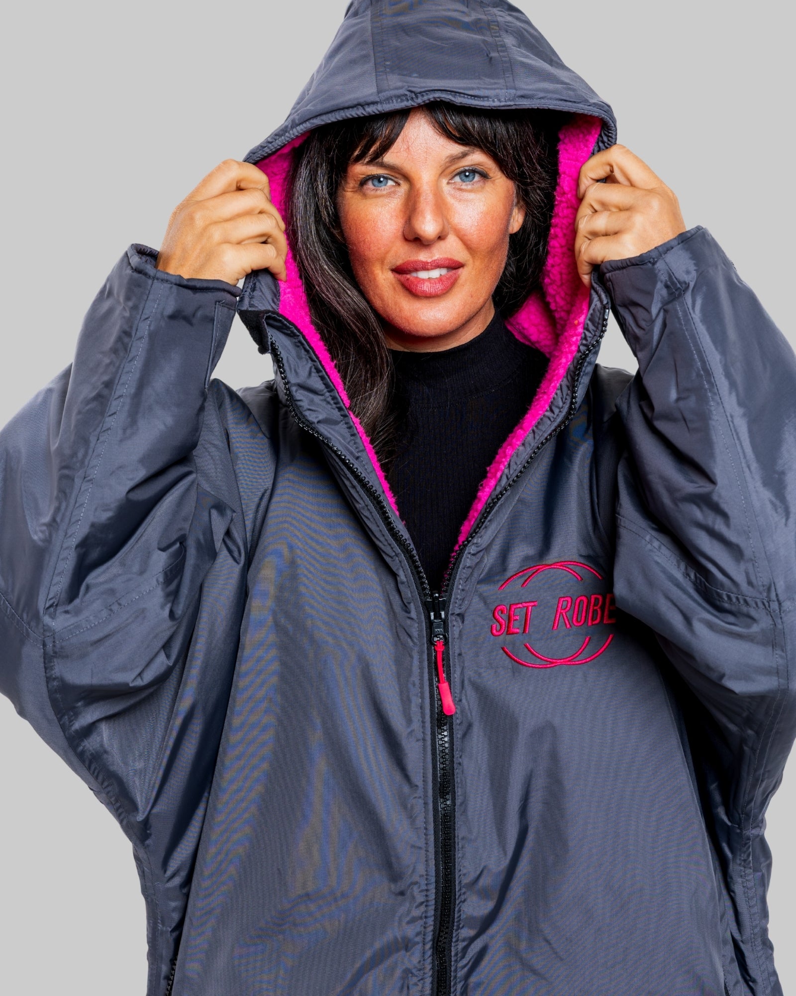 Model wearing a RuggaRobe slate grey change robe with pink fleece interior on a grey background