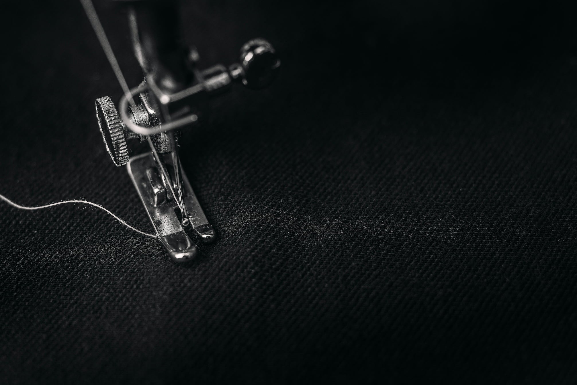 Black and white image of a sewing machine close up sewing fabric