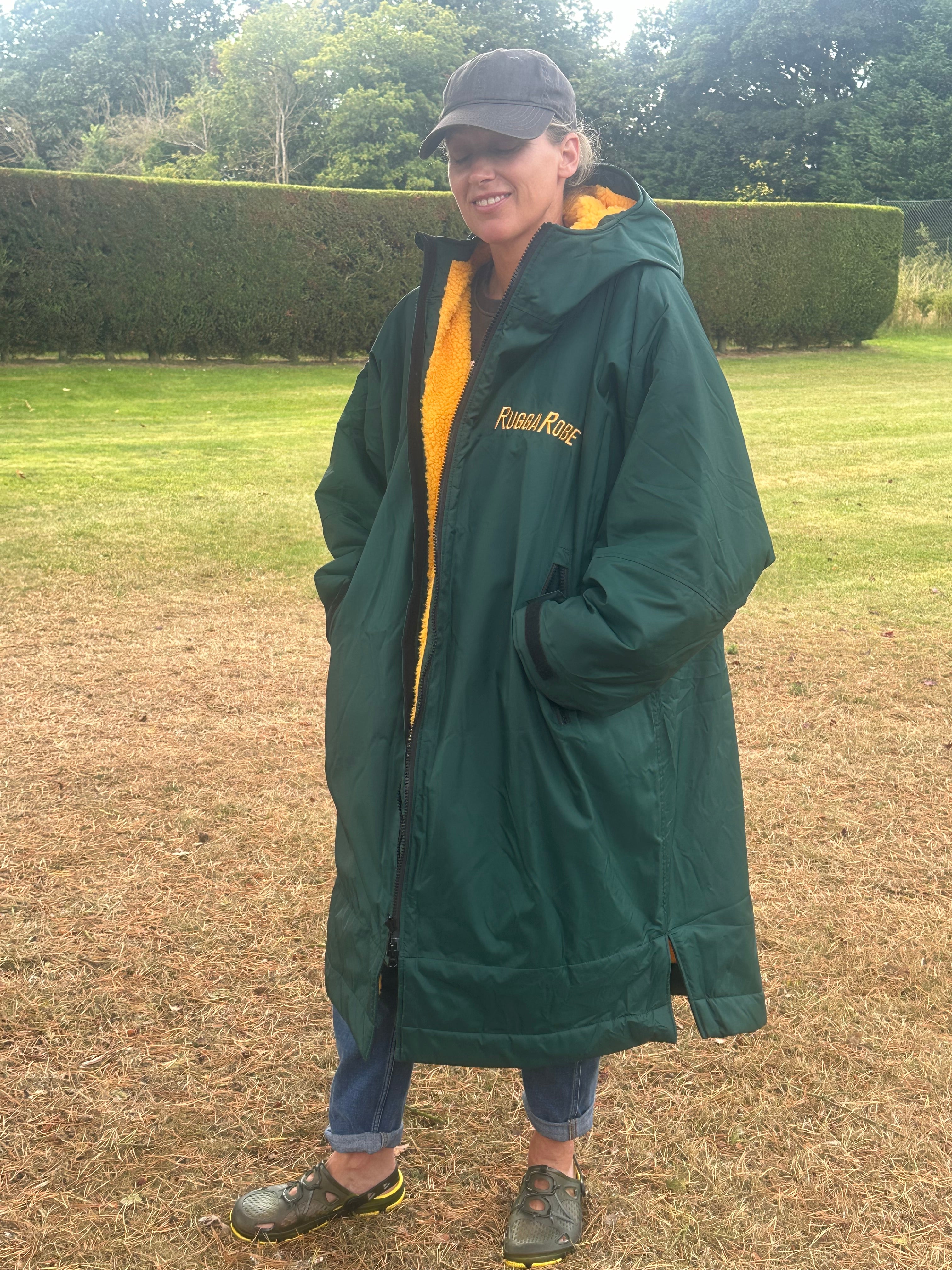 Person wearing a green with gold fleece change robe in a field