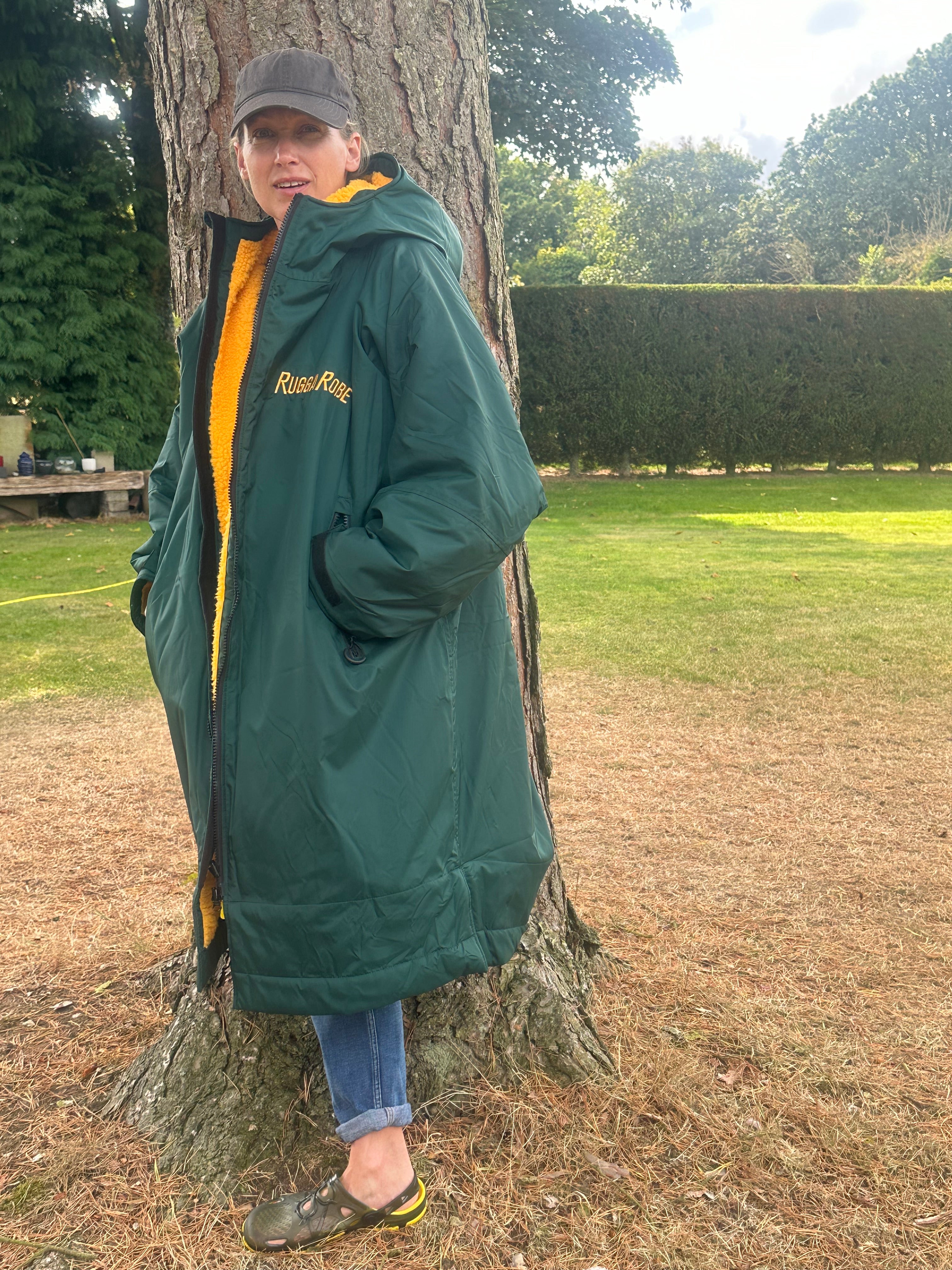 Person wearing a green with gold fleece change robe eith ruggarobe branding in a field 